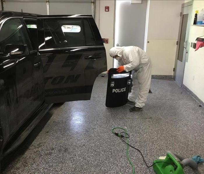 SERVPRO technician in PPE cleaning a cop car